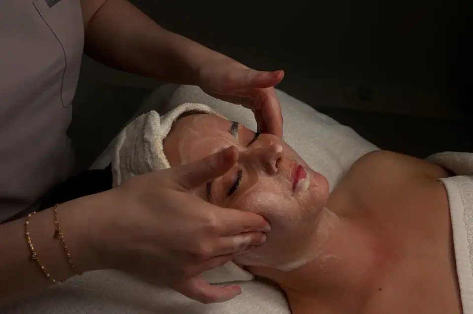 A therapist performing a facial massage in a treatment room
