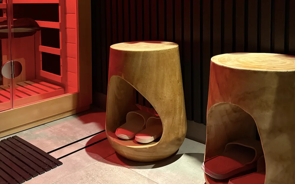 Two round timber stools beside an infrared sauna