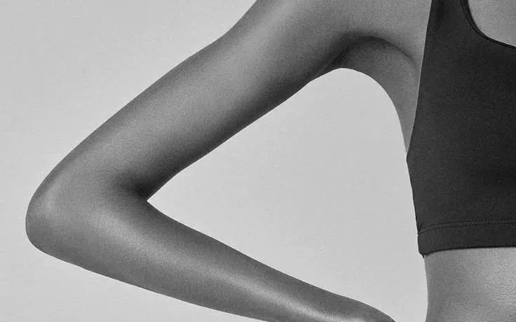 Black and white photo of a woman in a crop top with her hand on her waist