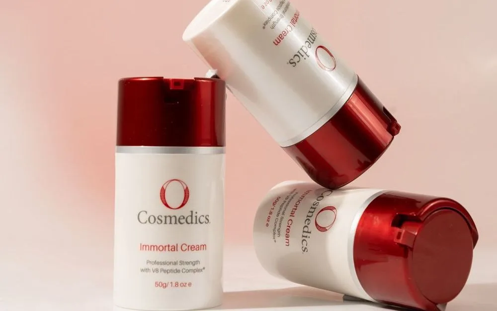 O Cosmedics cream bottles stacked against a soft pink background